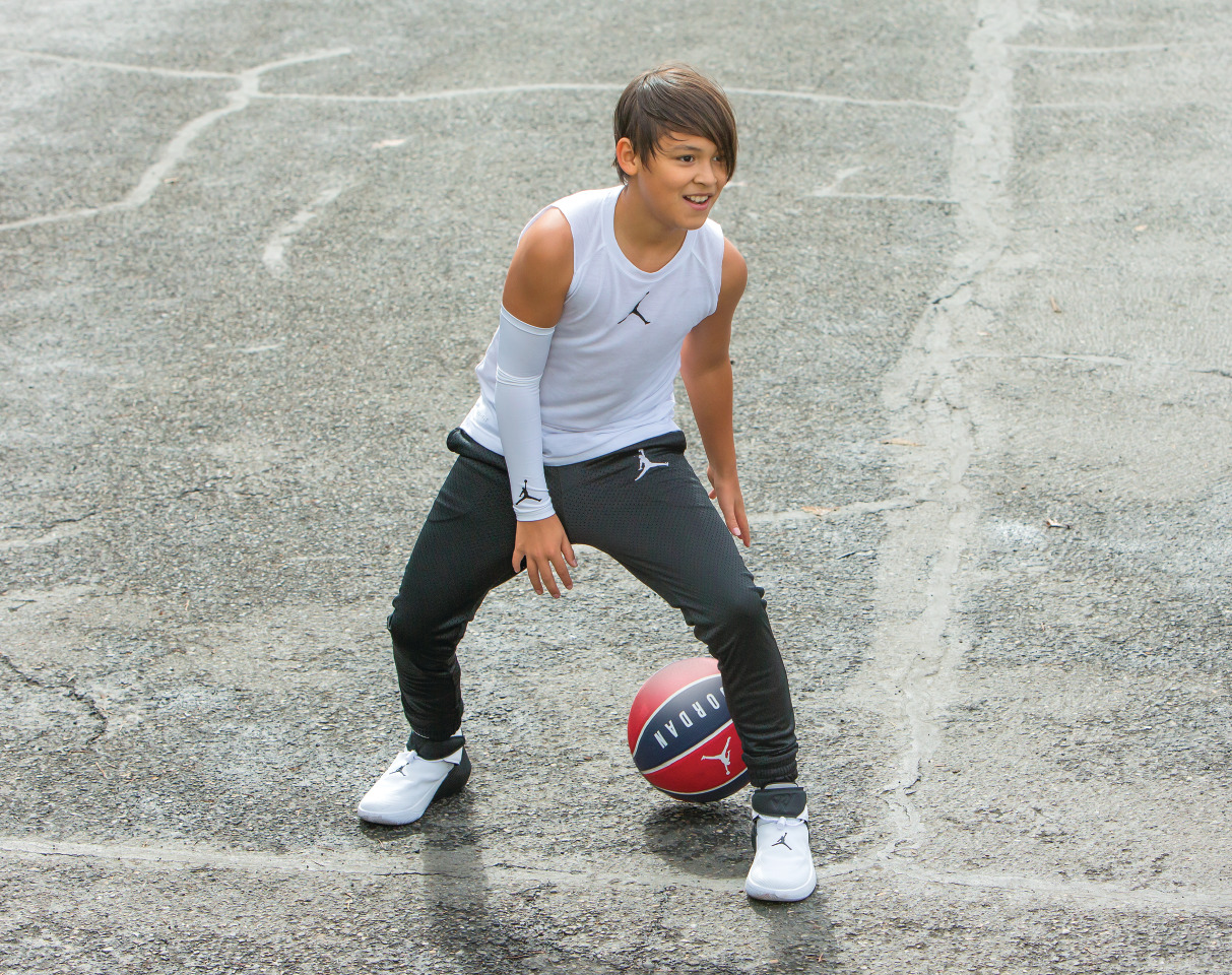 Un garçon dribblant avec un ballon entre les jambes et portant une tenue Jordan complète
